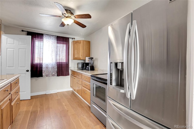 kitchen with a textured ceiling, ceiling fan, light hardwood / wood-style flooring, and appliances with stainless steel finishes