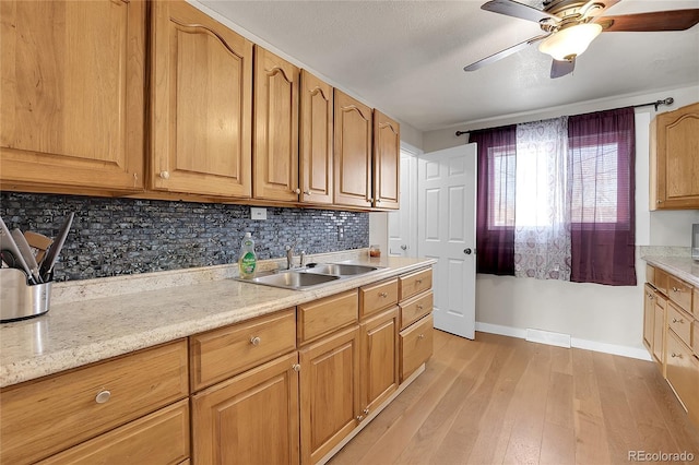 kitchen featuring light stone countertops, light wood-type flooring, decorative backsplash, and sink