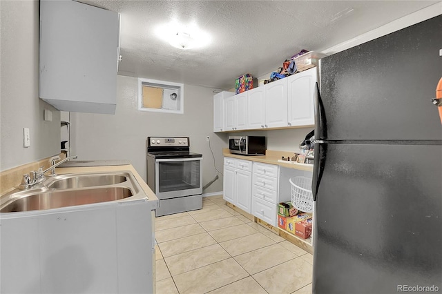 kitchen with stainless steel appliances, sink, white cabinets, a textured ceiling, and light tile patterned flooring