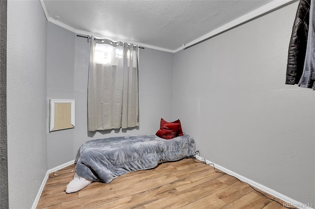 bedroom with a textured ceiling, hardwood / wood-style floors, and crown molding