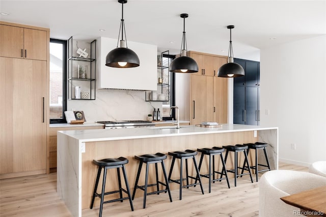 kitchen with pendant lighting, a large island with sink, a breakfast bar area, and light wood-type flooring