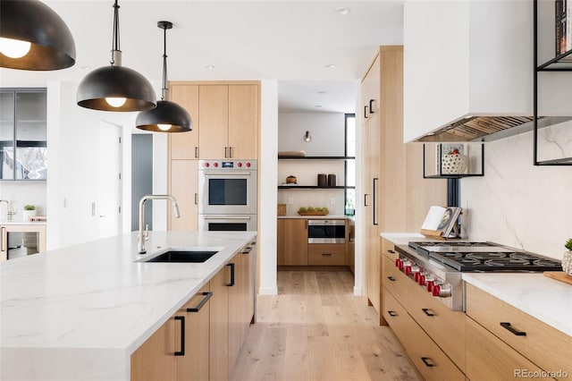 kitchen featuring light stone countertops, extractor fan, stainless steel gas cooktop, hanging light fixtures, and sink