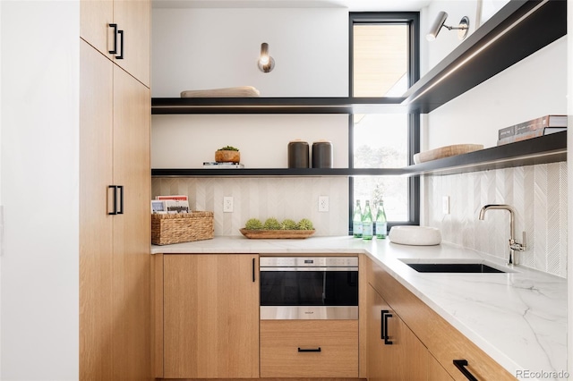 kitchen featuring sink, oven, a wealth of natural light, and light brown cabinets