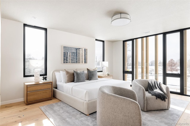 bedroom featuring light wood-type flooring and expansive windows