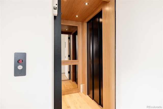 corridor featuring elevator, hardwood / wood-style floors, and wood ceiling