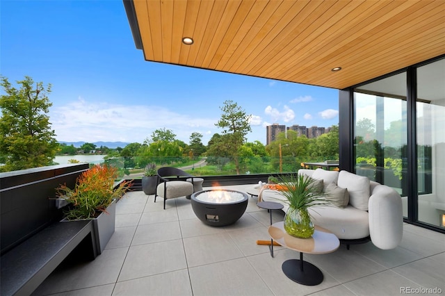 view of patio with a water view and an outdoor living space with a fire pit