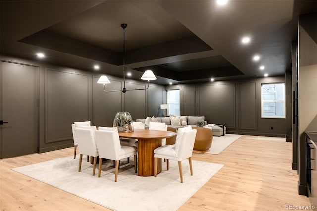 dining room with light hardwood / wood-style flooring and a raised ceiling