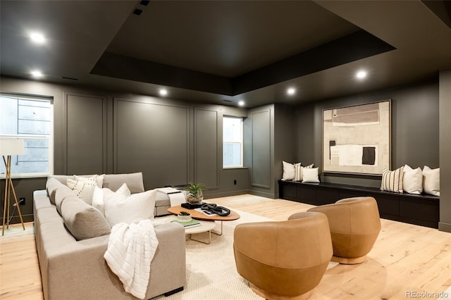 home theater room with light hardwood / wood-style flooring and a tray ceiling