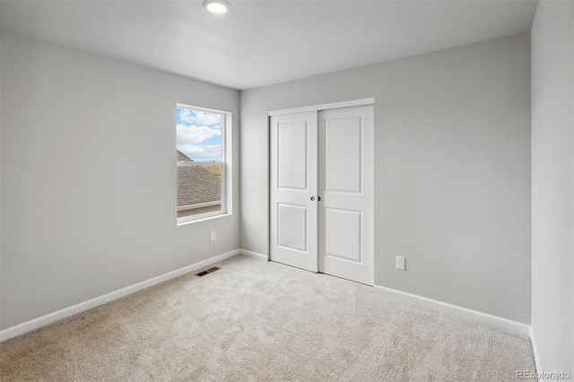 unfurnished bedroom with light colored carpet and a closet