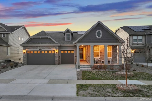 8751 S Wenatchee Ct, Aurora, CO 80016 - view of front of home with stone siding, covered porch, a garage, driveway, and solar panels