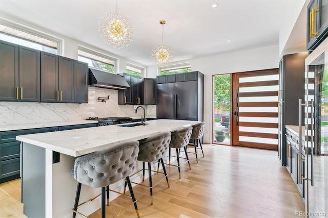 2280 W 42nd Ave, Denver, CO 80211 - kitchen featuring under cabinet range hood, a sink, a chandelier, decorative backsplash, and plenty of natural light