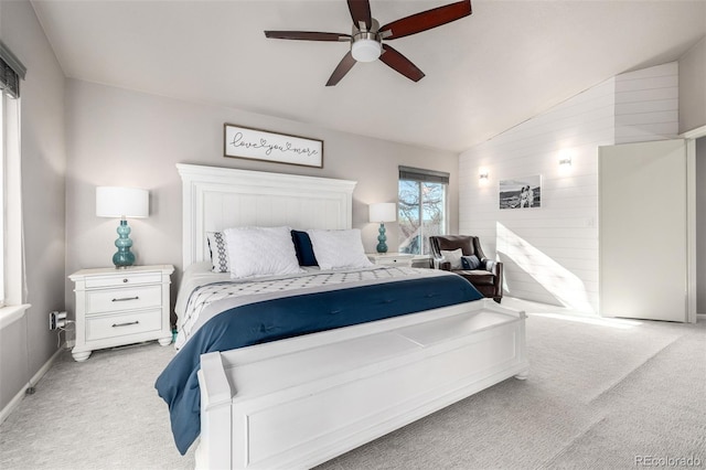carpeted bedroom with a ceiling fan, vaulted ceiling, and wood walls