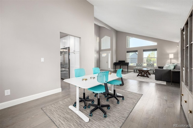 office area with baseboards, high vaulted ceiling, and wood finished floors