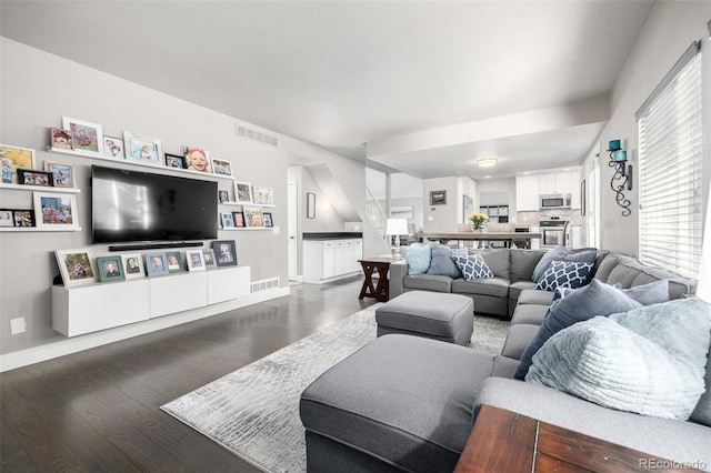 living area with visible vents, baseboards, and wood finished floors