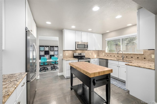 kitchen featuring stainless steel appliances, decorative backsplash, a sink, and wood finished floors