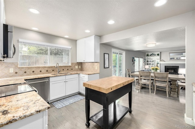kitchen with light wood-type flooring, a sink, white cabinetry, and dishwasher