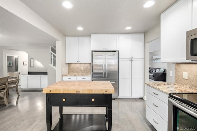 kitchen featuring backsplash, stainless steel appliances, butcher block counters, and light wood finished floors