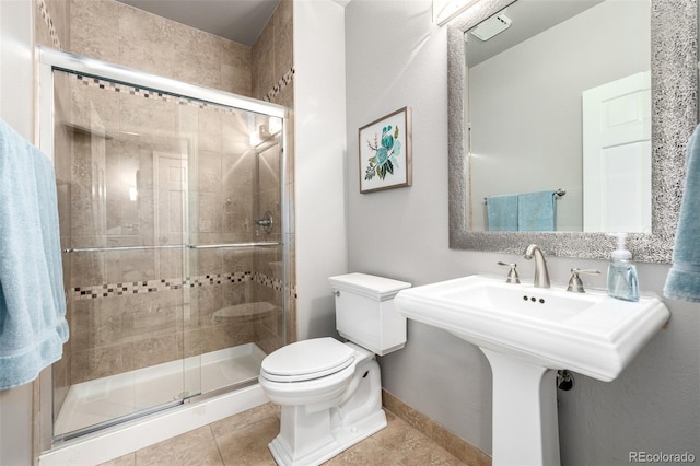 full bath featuring toilet, baseboards, tile patterned floors, a sink, and a stall shower