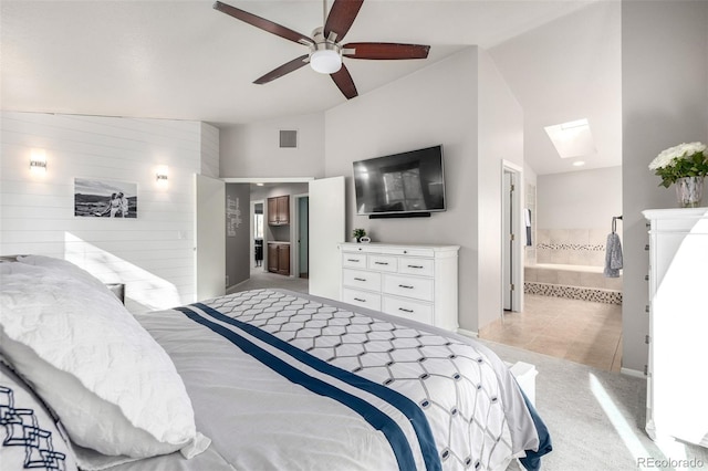 bedroom featuring light carpet, vaulted ceiling with skylight, light tile patterned floors, ensuite bathroom, and visible vents