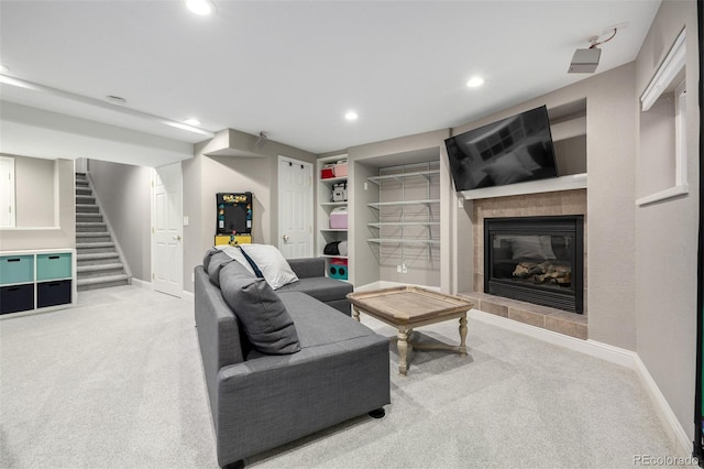 carpeted living area with recessed lighting, baseboards, stairway, and a tile fireplace