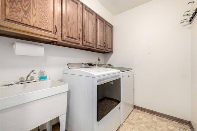 clothes washing area with cabinet space, independent washer and dryer, a sink, baseboards, and light floors