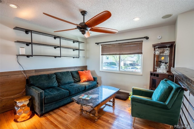 living area with wood finished floors, a textured ceiling, ceiling fan, baseboards, and recessed lighting