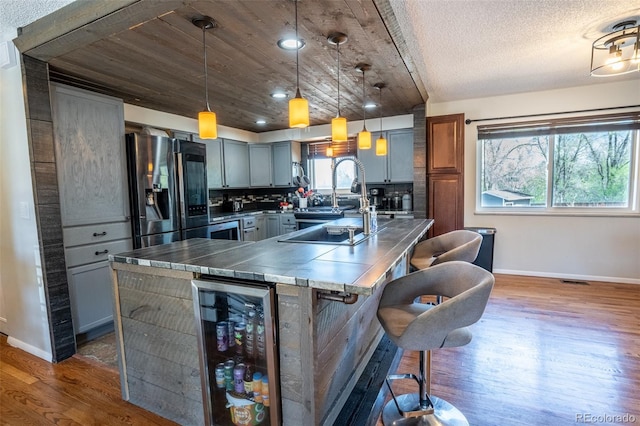 kitchen with stainless steel fridge, a sink, baseboards, wood finished floors, and beverage cooler