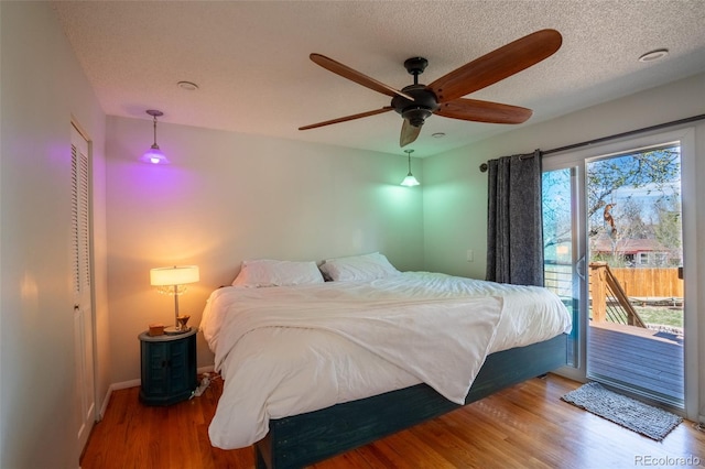 bedroom with a textured ceiling, baseboards, a ceiling fan, wood finished floors, and access to outside