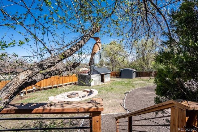 view of yard featuring a fenced backyard, an outdoor structure, a fire pit, and a shed