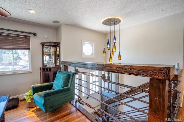 interior space with a wealth of natural light, baseboards, wood finished floors, and a textured ceiling