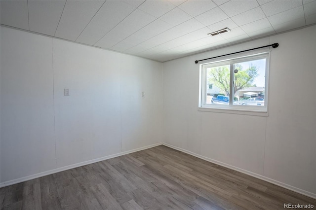 unfurnished room with wood finished floors, visible vents, and baseboards