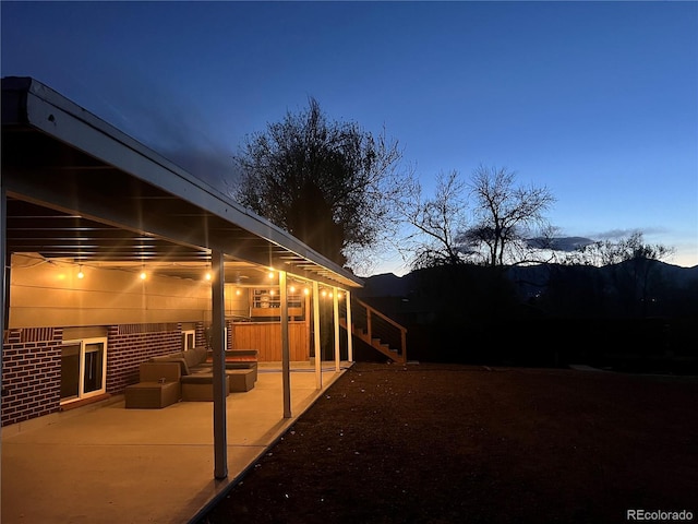 view of side of property with brick siding, a patio area, stairway, and an outdoor living space