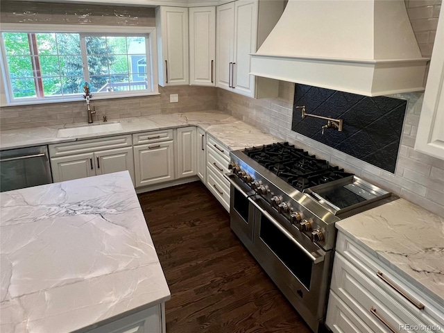 kitchen featuring stainless steel appliances, a sink, premium range hood, and white cabinets