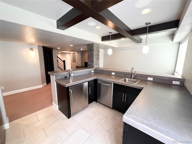 kitchen with stainless steel dishwasher, a sink, stainless steel counters, dark cabinets, and beamed ceiling