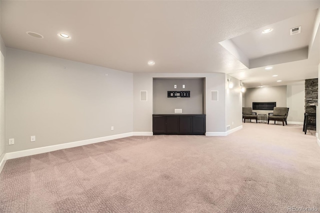unfurnished living room featuring a fireplace, recessed lighting, light carpet, baseboards, and a tray ceiling