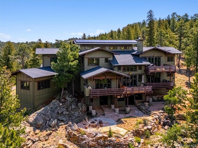 3395 Timbergate Trl, Evergreen, CO 80439 - rear view of property with an outdoor fire pit, a wooded view, a wooden deck, a chimney, and a patio area