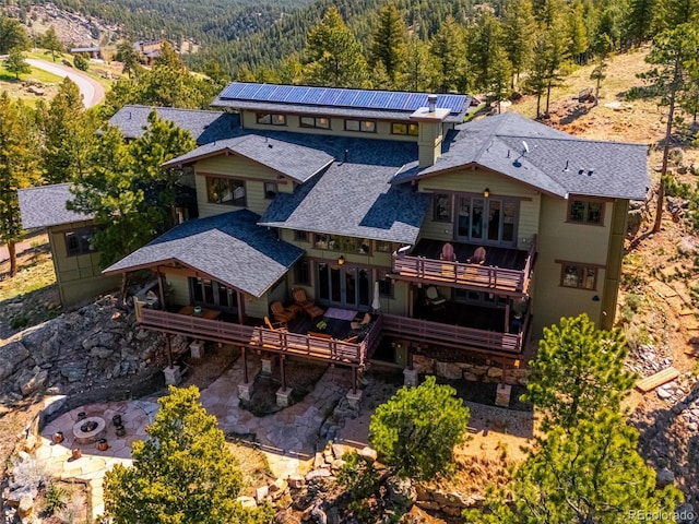 3395 Timbergate Trl, Evergreen, CO 80439 - rear view of property featuring a forest view, a patio area, a deck with mountain view, a shingled roof, and a balcony