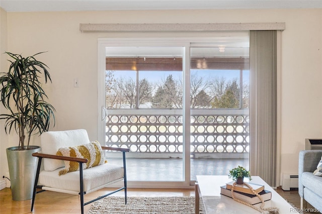 living area featuring a baseboard heating unit and hardwood / wood-style floors