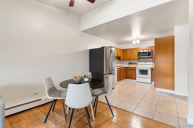 kitchen with a baseboard radiator, sink, ceiling fan, stainless steel appliances, and light wood-type flooring