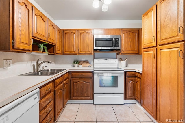 kitchen featuring sink, light tile patterned floors, and white appliances