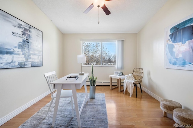 home office with baseboard heating, ceiling fan, light hardwood / wood-style flooring, and a textured ceiling