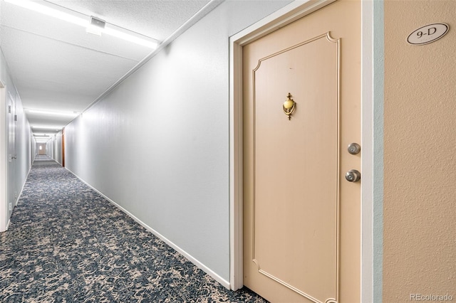 corridor with carpet floors and a textured ceiling