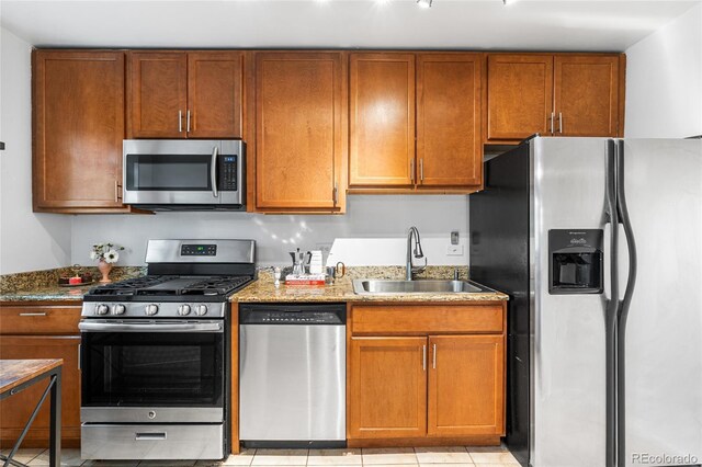 2100 N Franklin St Unit 5, Denver, CO 80205 - kitchen featuring appliances with stainless steel finishes, light stone counters, brown cabinets, and light tile patterned floors