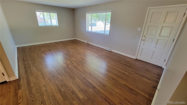 spare room featuring plenty of natural light and dark wood-type flooring