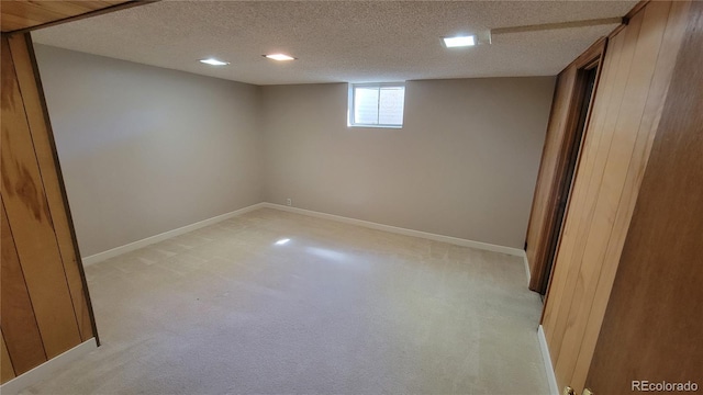 basement featuring light carpet and a textured ceiling