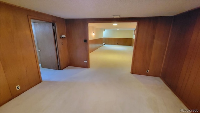 hallway featuring light carpet and wooden walls