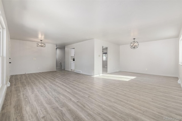 unfurnished living room with light hardwood / wood-style flooring and a chandelier