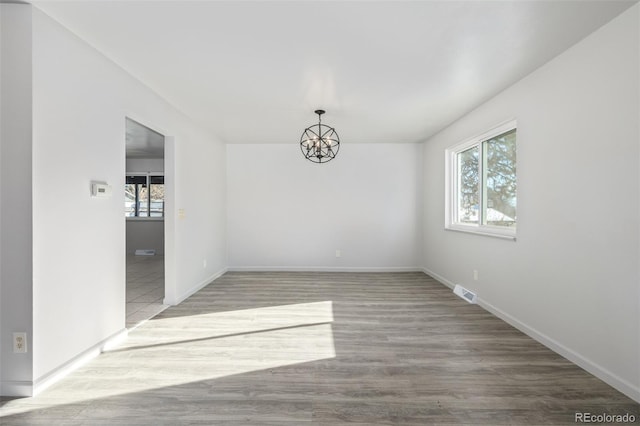 unfurnished room featuring hardwood / wood-style floors and a chandelier