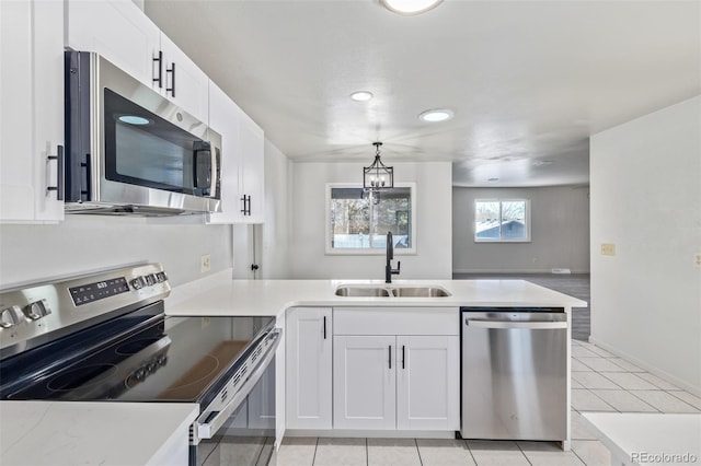 kitchen with white cabinetry, sink, stainless steel appliances, kitchen peninsula, and pendant lighting