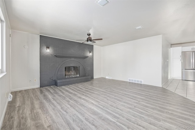 unfurnished living room with ceiling fan, light wood-type flooring, and a fireplace